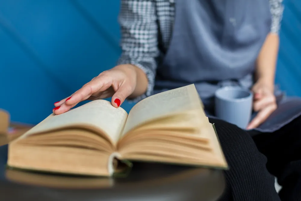 close-up-book-woman-holding-mug