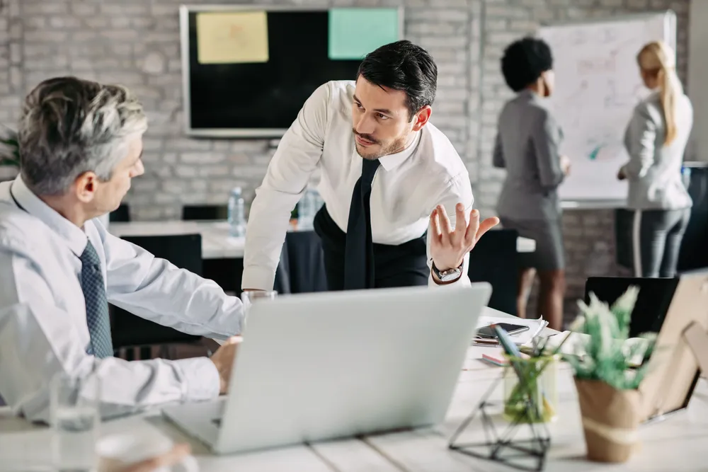 young-serious-businessman-talking-his-male-colleague-office-there-are-people-working-background (1)
