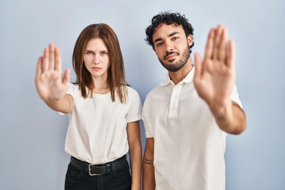 young-couple-wearing-casual-clothes-standing-together-doing-stop-sing-with-palm-hand-warning-expression-with-negative-serious-gesture-face